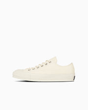 Side view of a cream canvas Chuck Taylor Canvas Ox sneaker on a white background.