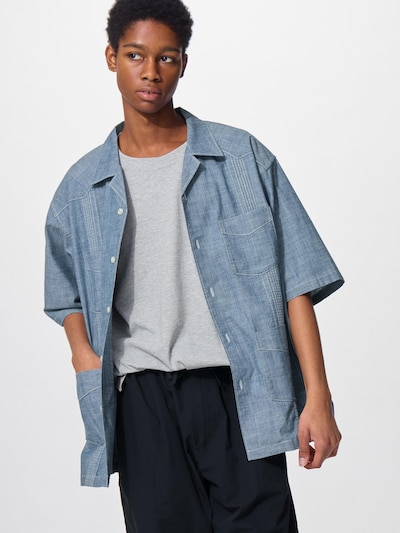 A model wearing a light blue Cuba shirt with mid-length sleeves over a gray T-shirt.