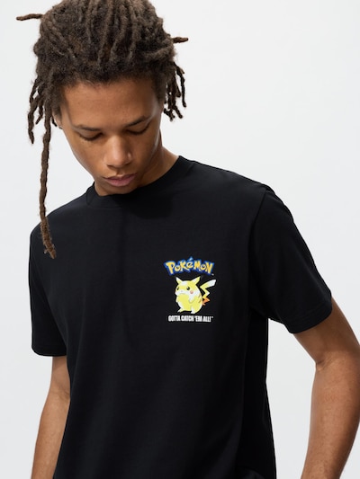 Model wearing a black men's cotton T-shirt with a small Pokémon Pikachu graphic on the left chest.