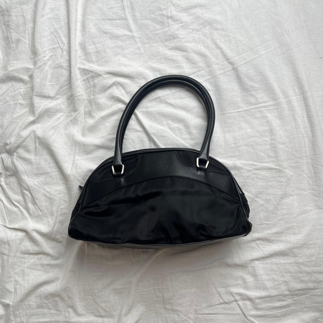Black PRADA nylon shoulder bag laid on a white sheet, showing the front and handles.