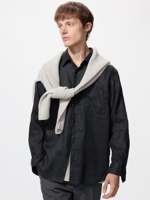A model wearing a black linen shirt with a light-colored sweater draped over his shoulders.