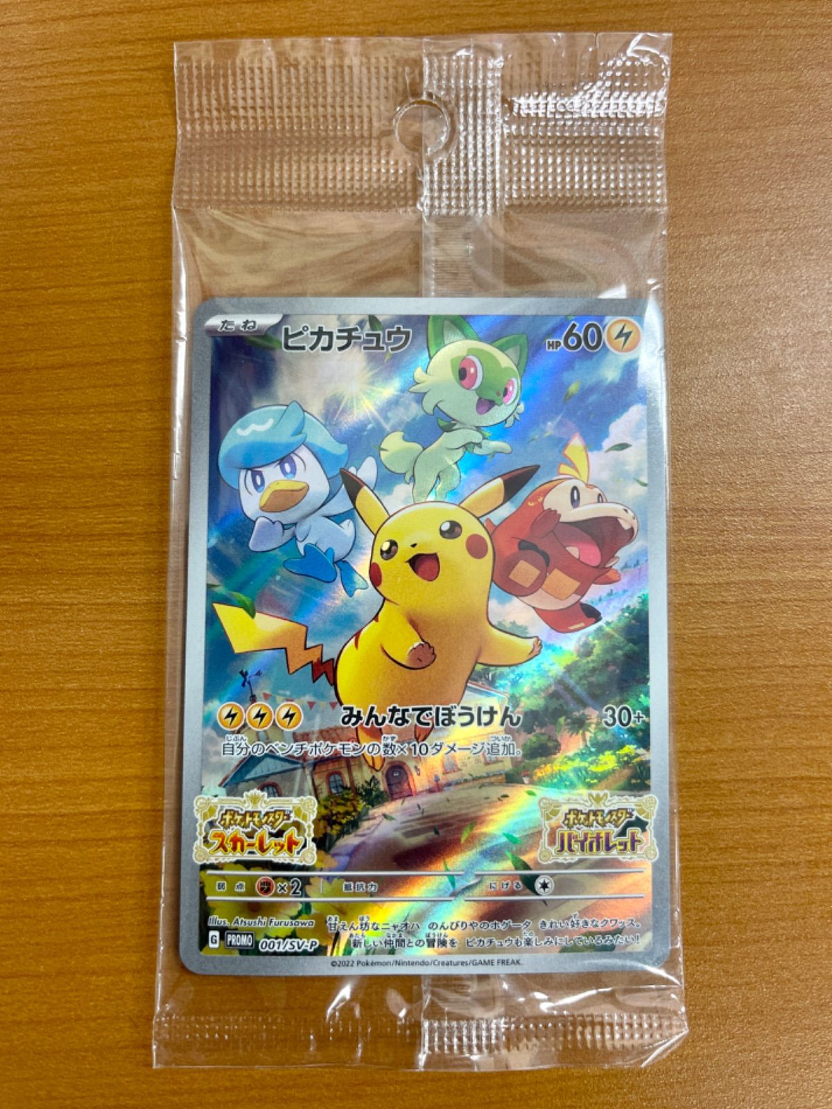 Unopened Pikachu promotional Pokémon trading card sealed in a clear plastic sleeve on a wooden surface.