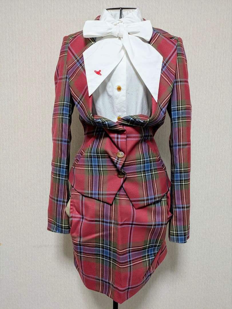 Red tartan Vivienne Westwood jacket and skirt set displayed on a dress form with a white blouse and large bow.