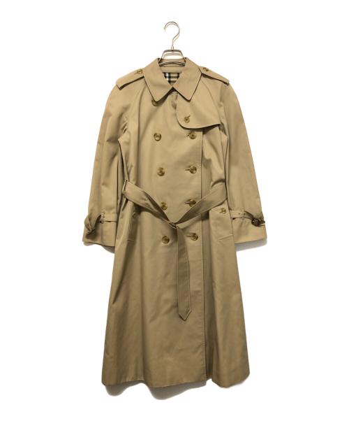 Beige cotton women's trench coat hanging on a hanger against a white background.